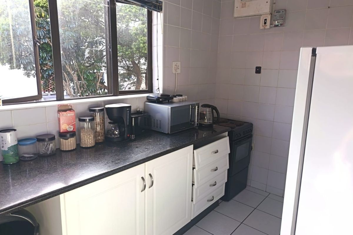 A functional kitchen featuring white cabinetry, granite countertops, a tiled backsplash, and an integrated electric stove.