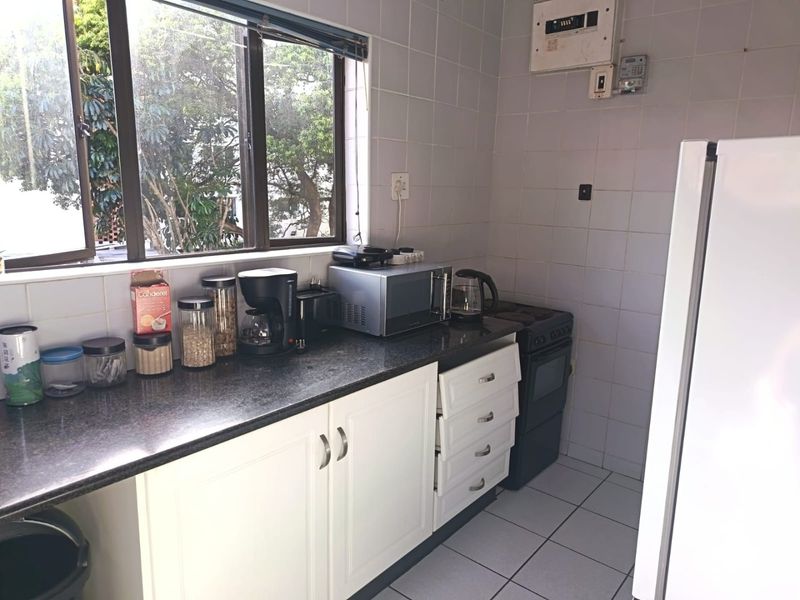 A functional kitchen featuring white cabinetry, granite countertops, a tiled backsplash, and an integrated electric stove.