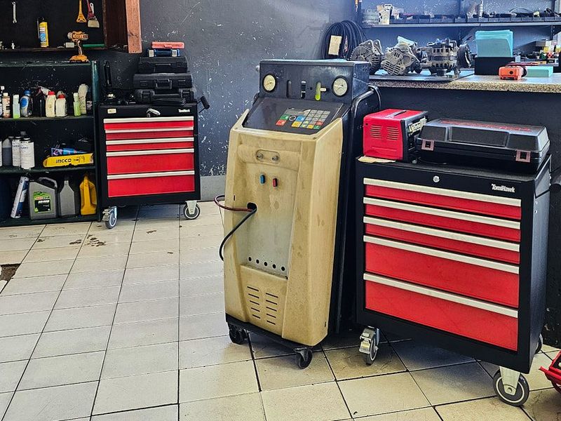 A functional commercial garage workspace featuring tiled flooring and a built-in service counter, suitable for automotive maintenance and repair operations.