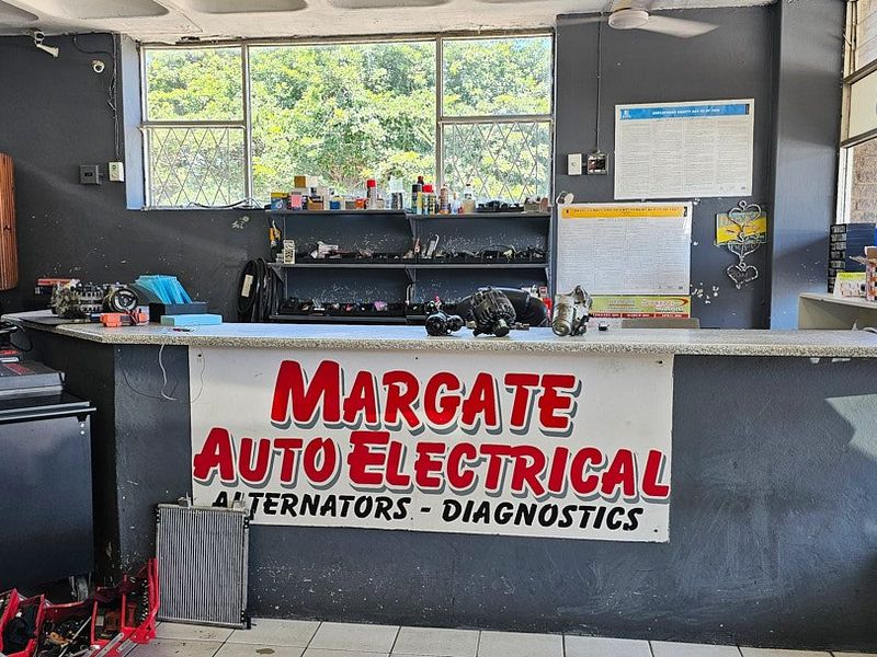 Commercial service counter area featuring tiled flooring, fixed shelving, and large windows, currently utilized as an auto electrical workshop reception.