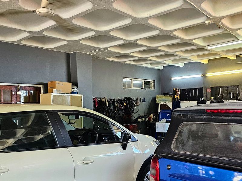 Commercial garage space featuring a distinctive waffle slab ceiling, fluorescent lighting, and functional wall-mounted storage areas.