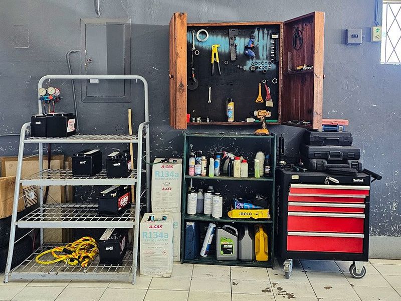 A functional utility or workshop space featuring tiled flooring, an electrical distribution board, and wall-mounted storage, currently utilized for equipment and maintenance storage.