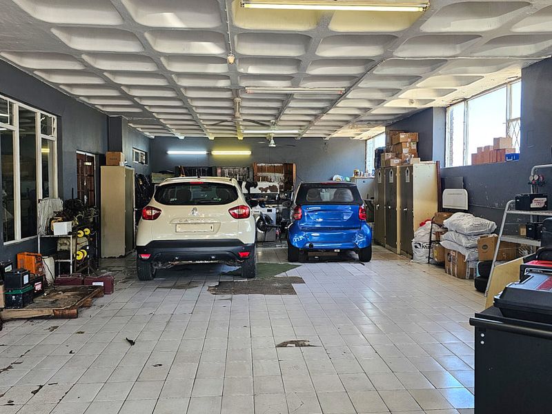 Spacious commercial garage featuring a waffle slab ceiling, durable ceramic tile flooring, and integrated fluorescent lighting, suitable for vehicle storage or workshop use.
