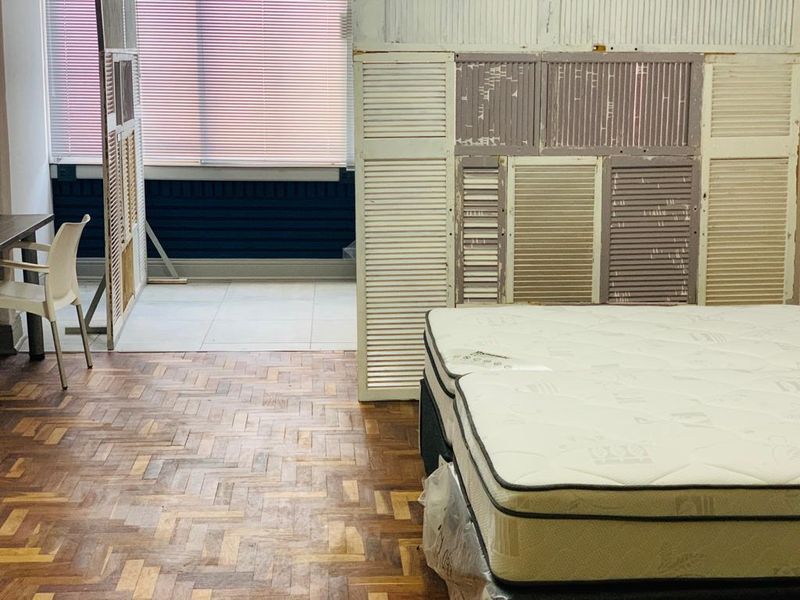 Bedroom featuring parquet flooring and a partitioned area with tiled floors and venetian blinds, requiring cosmetic updates to the wall finishes and flooring.