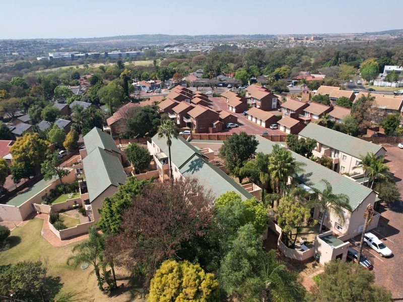 Aerial view of a residential apartment complex featuring multiple units with pitched roofs, paved driveways, and established garden areas.