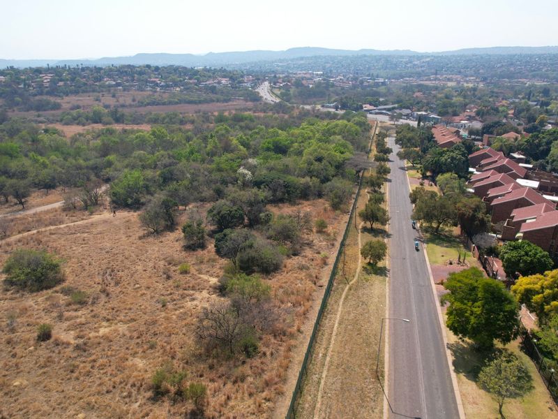 Aerial view of the surrounding neighborhood, featuring a paved access road, perimeter fencing, and expansive natural landscape.