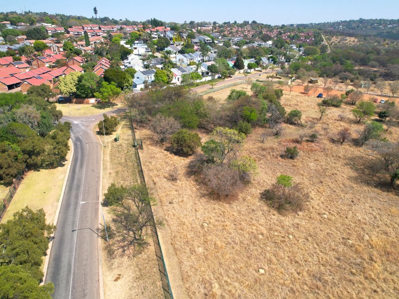 An aerial view showing the surrounding neighbourhood, local road infrastructure, and adjacent undeveloped land.