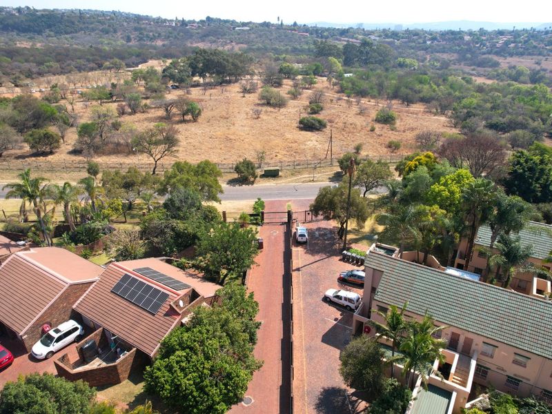 Aerial view of the apartment complex featuring paved driveways, tiled roofing with solar panels, and secure perimeter fencing.