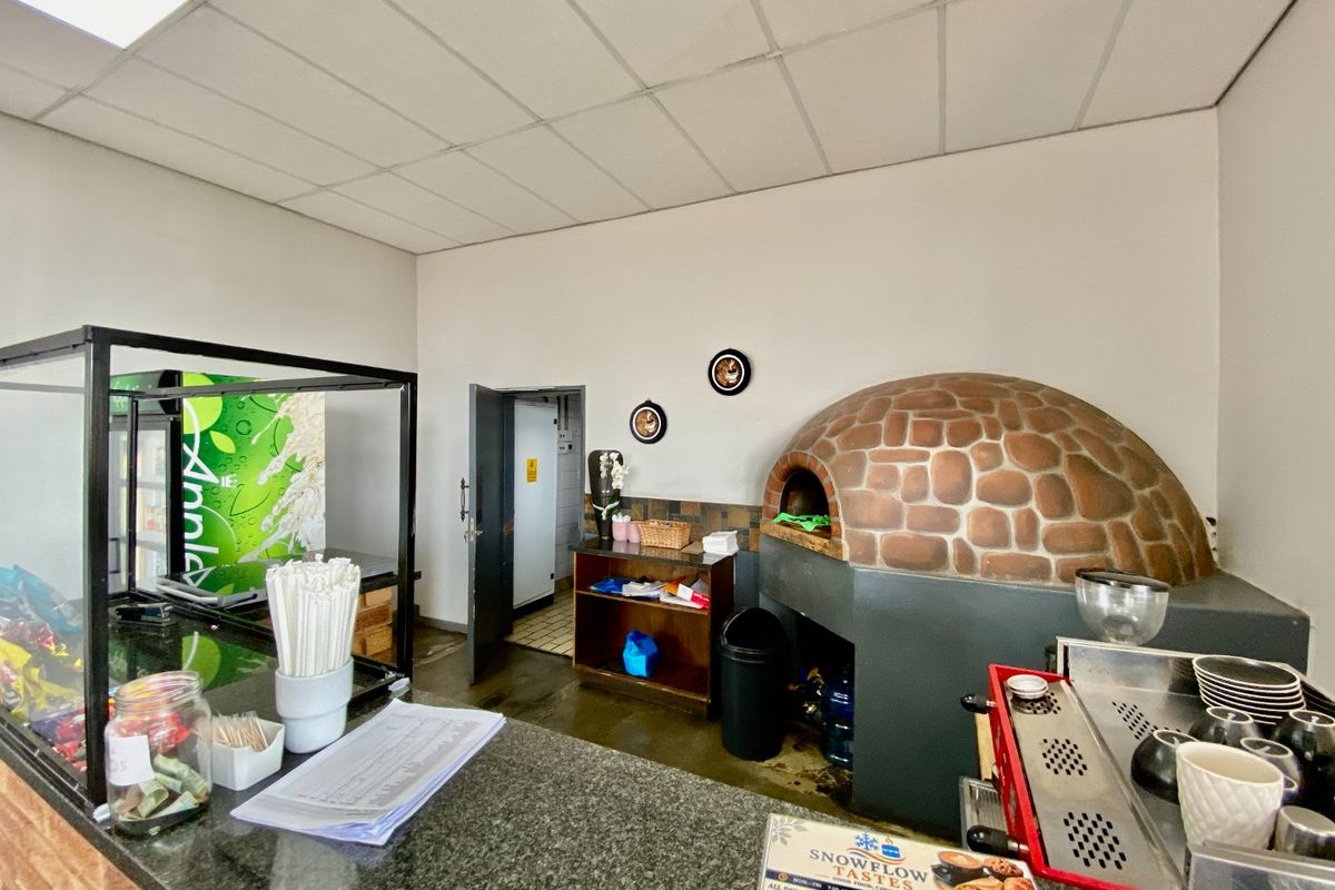 Commercial kitchen area featuring a built-in stone pizza oven, granite service counter, and drop ceiling, suitable for food preparation and service.