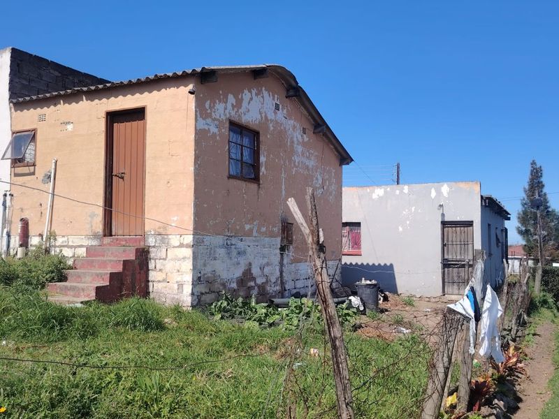 Front view of a detached residential property showing significant exterior wear, peeling paint, and basic masonry construction.