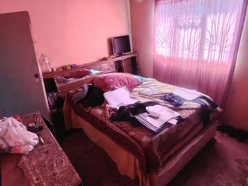A bedroom featuring a built-in headboard, requiring significant renovation and cosmetic updates to improve the overall condition and appeal of the space.