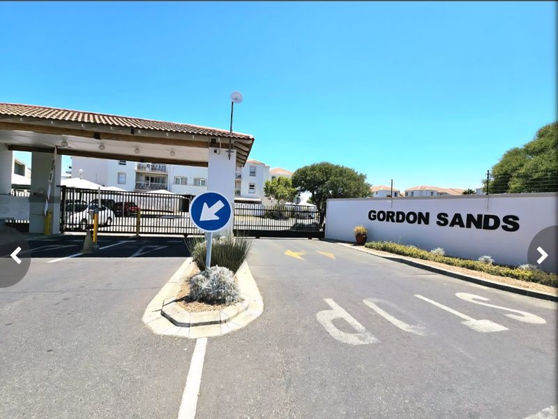 The entrance to Gordon Sands apartment complex featuring a secure gated access point, paved driveway, and clear signage.
