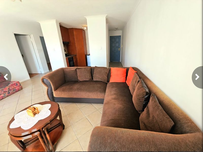 Open plan living area featuring tiled flooring and a compact kitchen with built-in cabinetry and appliances.