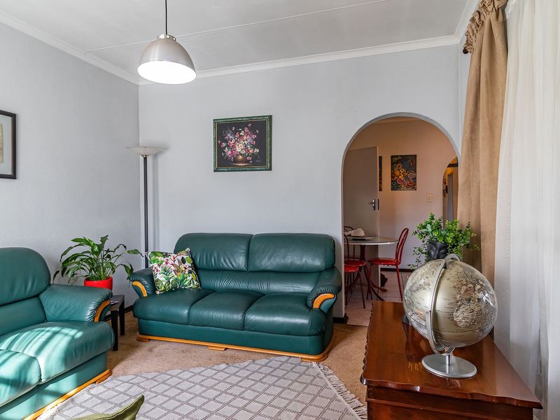 A comfortable living room featuring carpeted flooring, a coved ceiling, and an arched doorway leading to an adjacent dining area.
