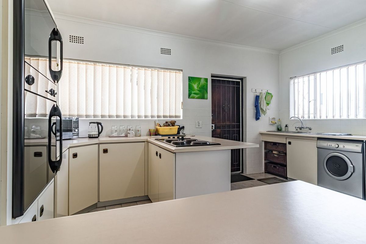 Functional kitchen featuring built-in oven, hob, double sink, and ample cabinetry with integrated laundry appliance space.