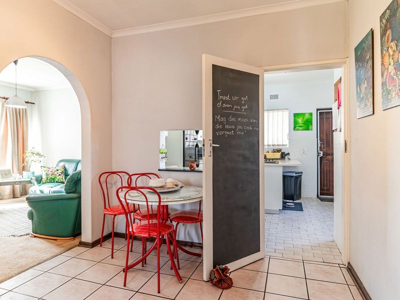 Open plan living area featuring tiled flooring, a decorative archway, and a chalkboard door leading into the kitchen space.