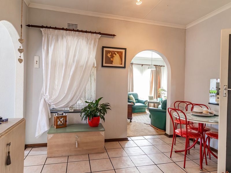 A living area featuring tiled flooring, arched architectural transitions, and a built-in chalkboard, connecting to an adjacent room.