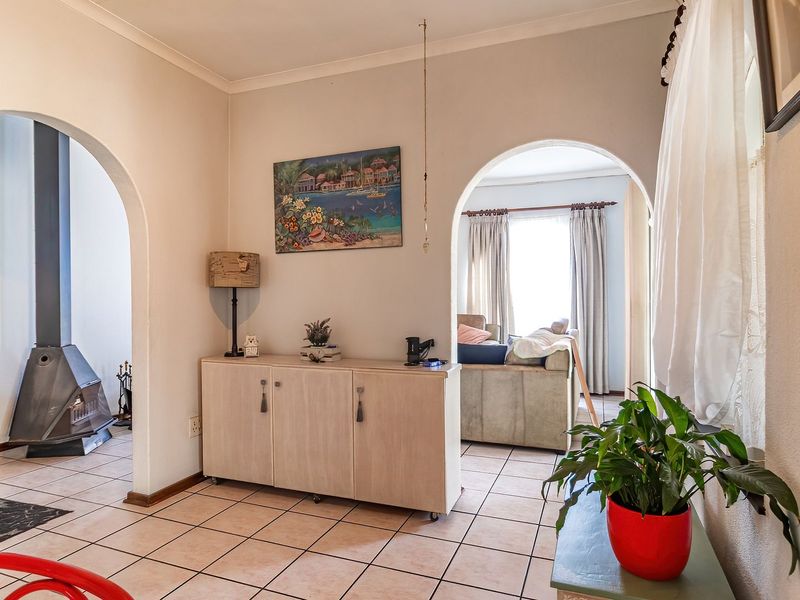 A living area featuring tiled flooring, distinctive arched doorways, and a modern freestanding fireplace, creating a connected and open layout.