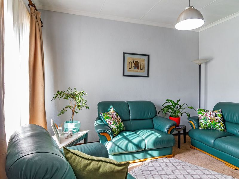 A comfortable living room featuring neutral wall finishes, carpeted flooring, and a central pendant light fixture.