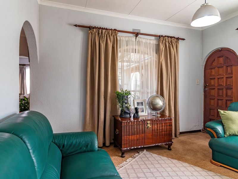 A living room featuring an arched doorway, timber panelled door, and coved ceilings, offering a traditional layout with carpeted flooring.