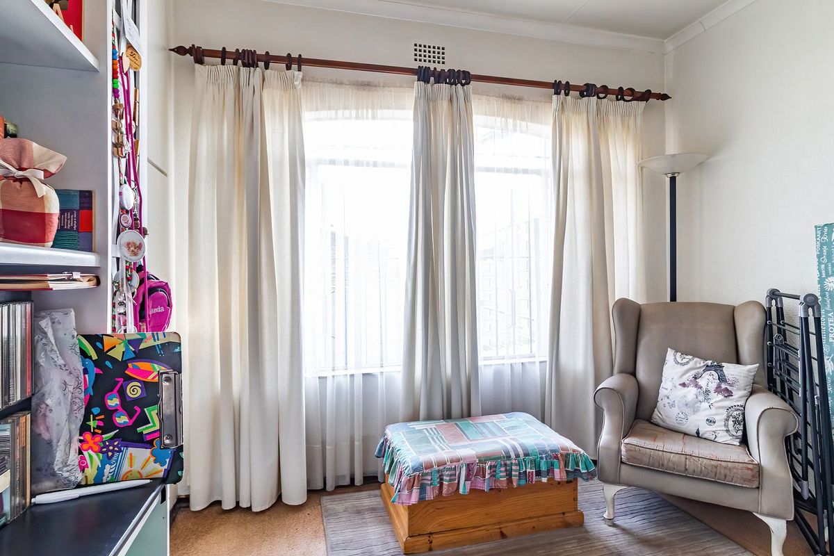 A bedroom featuring an arched window with curtain rod and built-in shelving, providing a functional space with natural light.