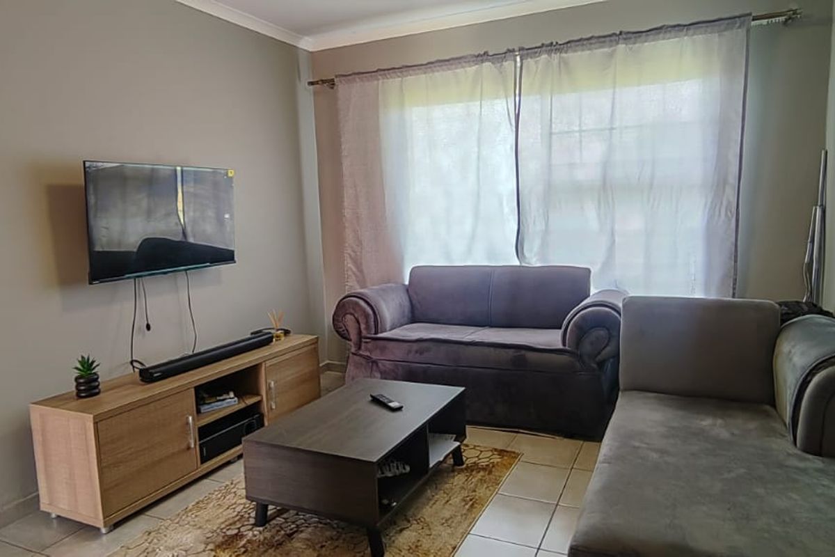 A functional living room featuring tiled flooring and a large window with curtain fixtures, providing a neutral base for interior design updates.