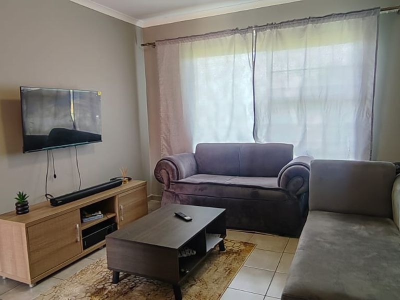 A functional living room featuring tiled flooring and a large window with curtain fixtures, providing a neutral base for interior design updates.