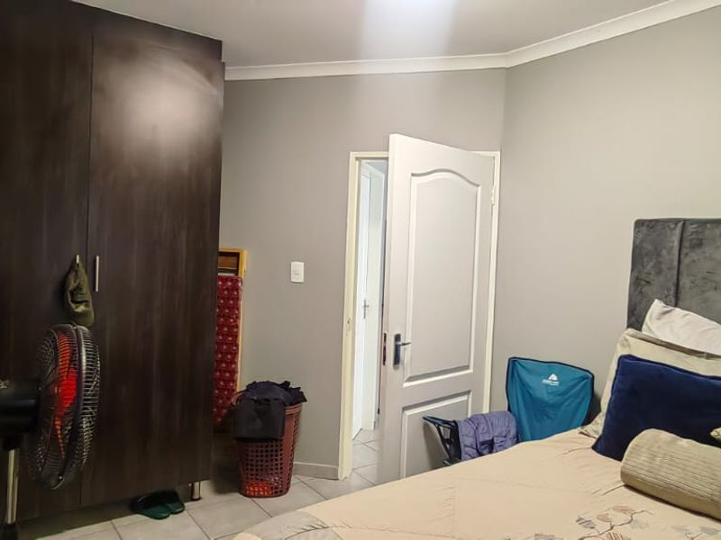 A bedroom featuring tiled flooring, a built-in dark wood wardrobe, and neutral wall finishes.