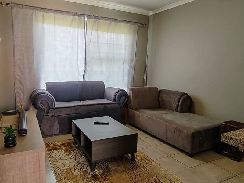A comfortable living room featuring tiled flooring, a granite breakfast counter, and neutral wall tones, providing a functional and inviting space.