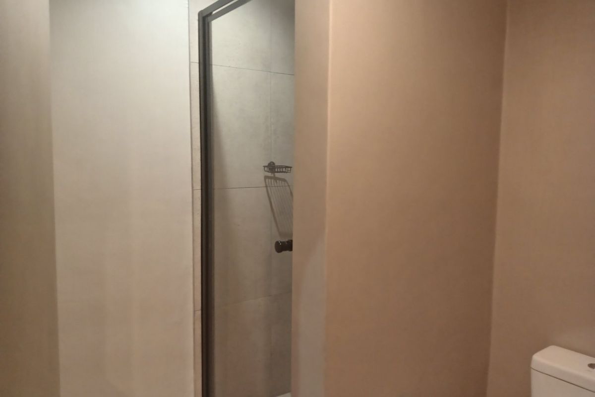 A clean, modern bathroom featuring a glass-enclosed shower with neutral wall tiles and a standard toilet.