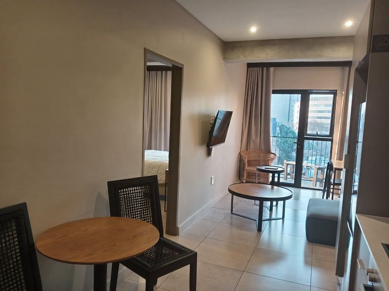 Open-plan living area featuring tiled flooring, recessed lighting, and direct access to a balcony through a sliding glass door.