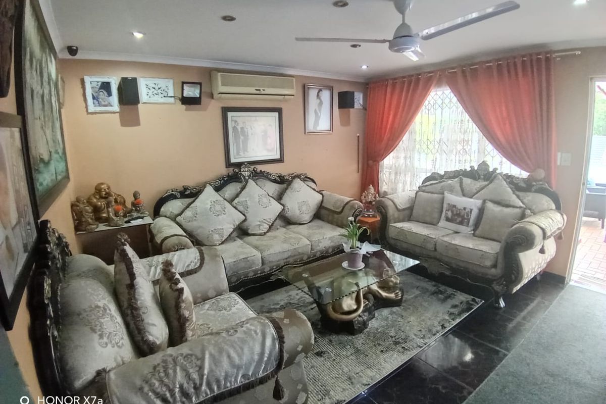 A comfortable living room featuring tiled flooring, recessed lighting, a ceiling fan, and a wall-mounted air conditioning unit for climate control.