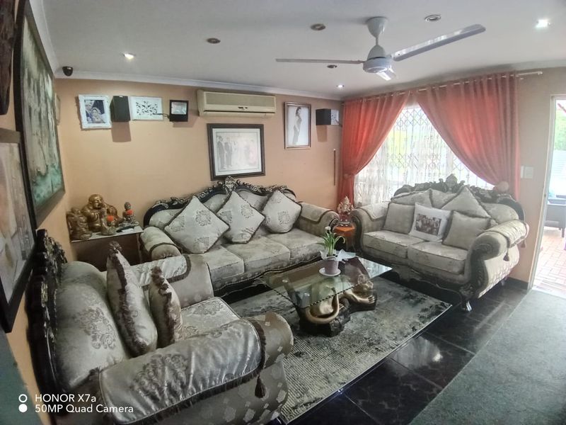 A comfortable living room featuring tiled flooring, recessed lighting, a ceiling fan, and a wall-mounted air conditioning unit for climate control.