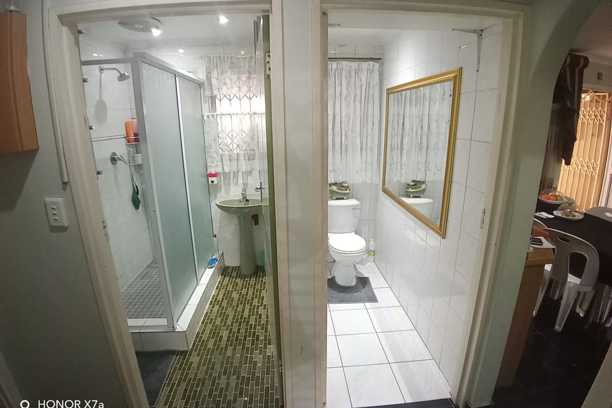A split-layout bathroom featuring a separate shower cubicle with pedestal basin and a dedicated toilet area with tiled finishes.