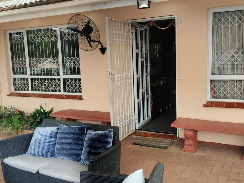 A covered patio area featuring brick paving, built-in concrete benches, and security gates, providing a functional outdoor space for relaxation.