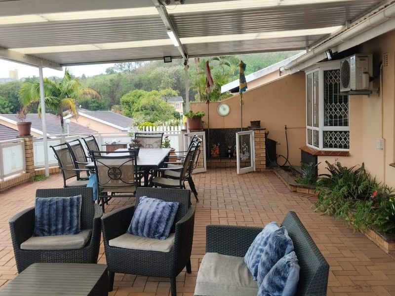 Spacious covered patio featuring brick paving, a built-in braai, and direct access to the home, ideal for outdoor entertaining and relaxation.