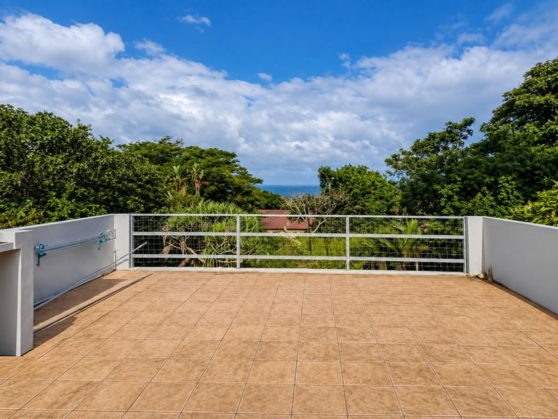 An open-air balcony featuring tiled flooring, a secure metal wire mesh railing, and a wall-mounted drying rack, offering pleasant outdoor space.
