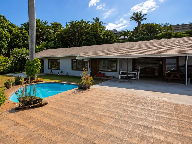 Rear exterior view featuring a swimming pool, tiled patio area, and a covered patio space adjacent to the main house structure.