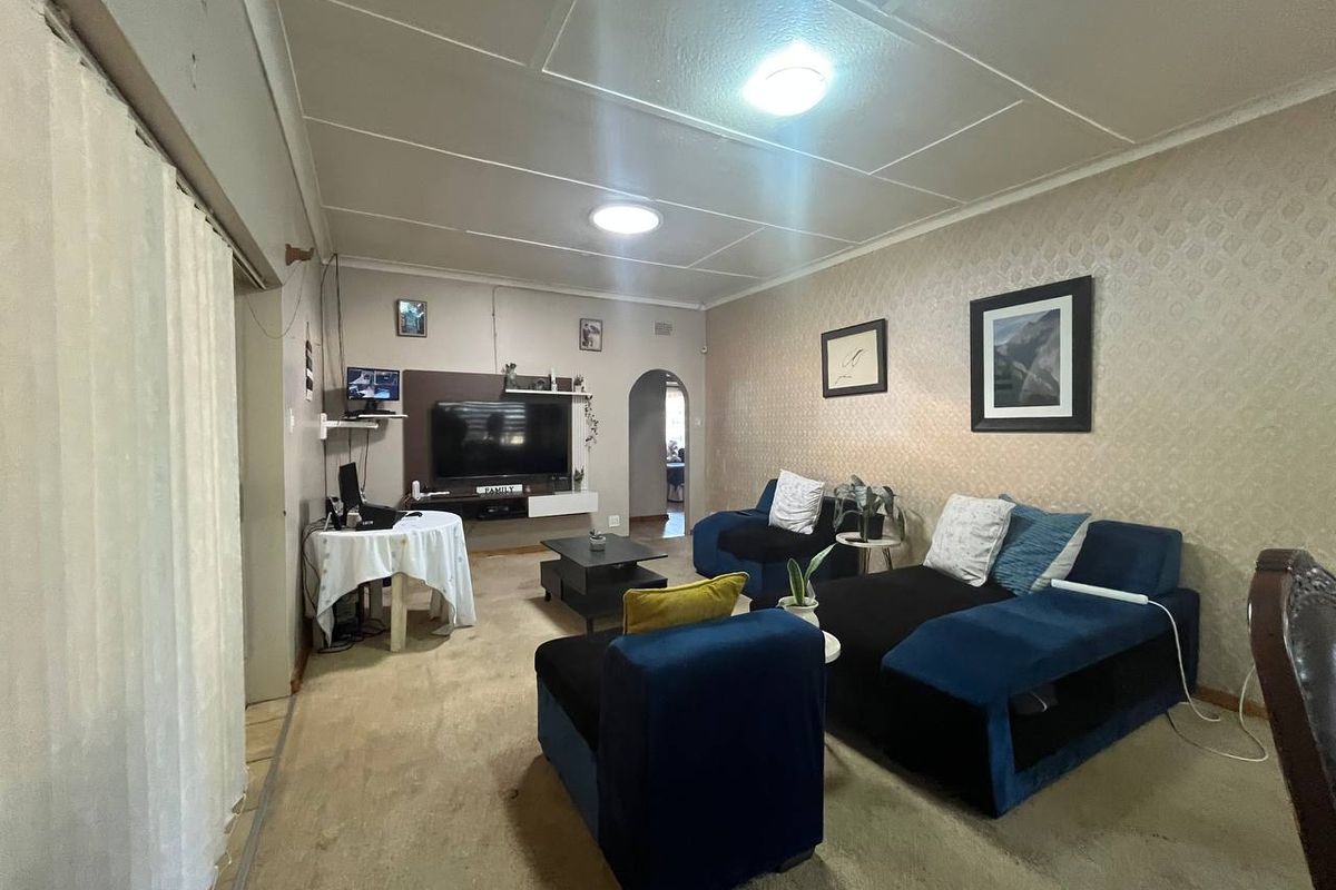 A living room featuring a built-in media unit, an arched doorway, and a tiled ceiling, offering a functional space with potential for modernization.