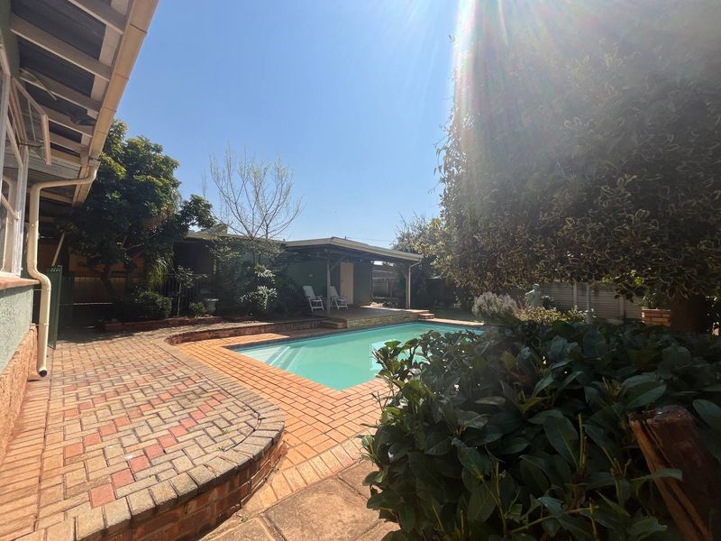 Outdoor pool area featuring a swimming pool, brick paved surround, and a covered patio space.