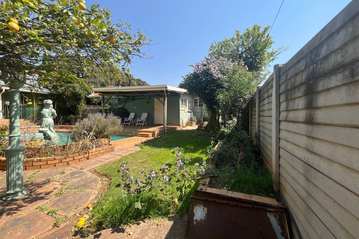 Rear garden area featuring a swimming pool, covered patio, and established landscaping enclosed by a precast concrete boundary wall.