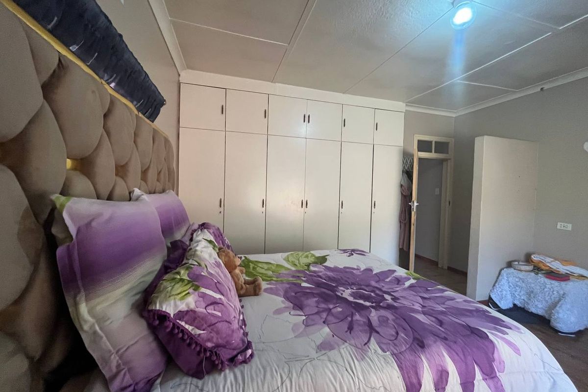 A bedroom featuring built-in white cupboards and a tiled ceiling, providing functional storage space.