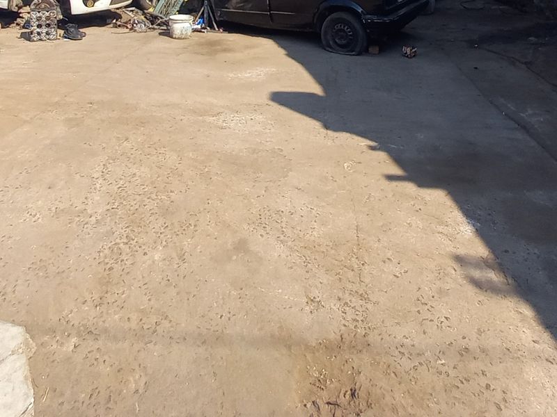 A view of a weathered concrete driveway surface showing signs of wear and cracking.