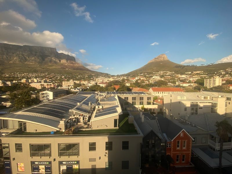 Elevated view overlooking a commercial building with rooftop solar panels and HVAC units, set against a scenic mountain backdrop.