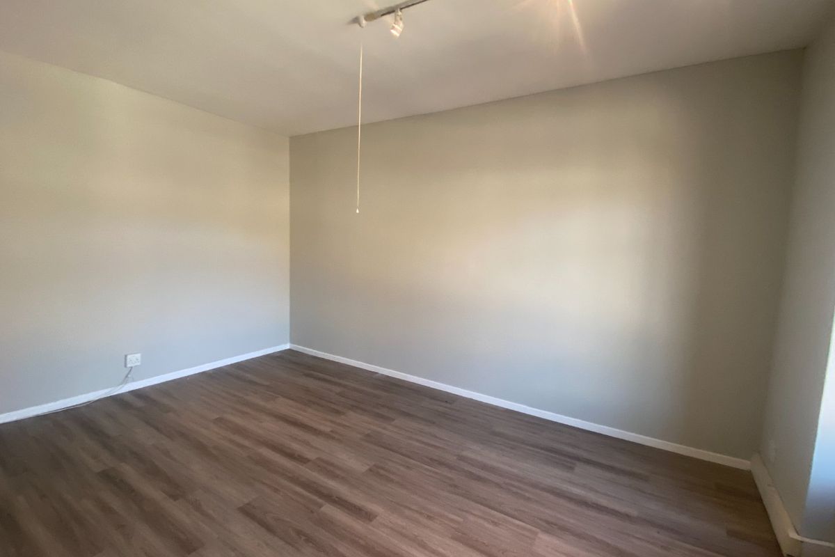 A clean, empty office space featuring modern laminate flooring and track lighting, providing a versatile environment for commercial use.