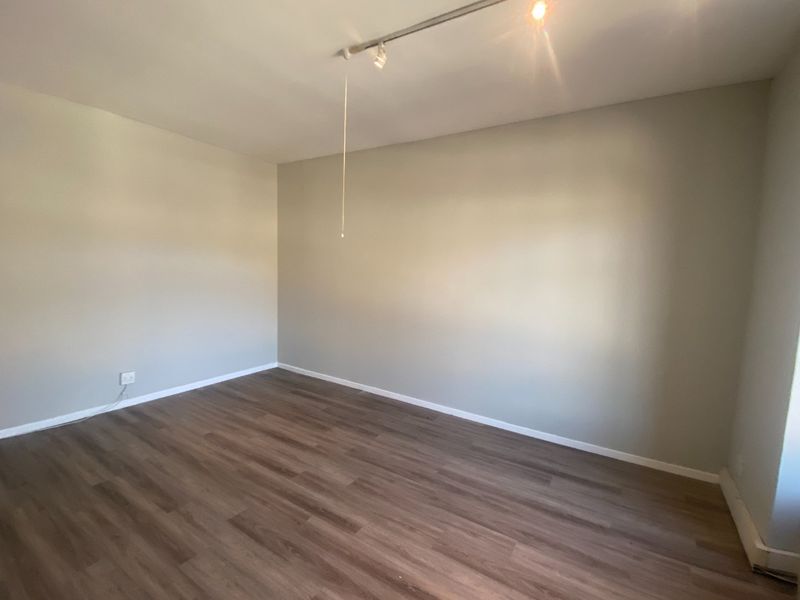 A clean, empty office space featuring modern laminate flooring and track lighting, providing a versatile environment for commercial use.
