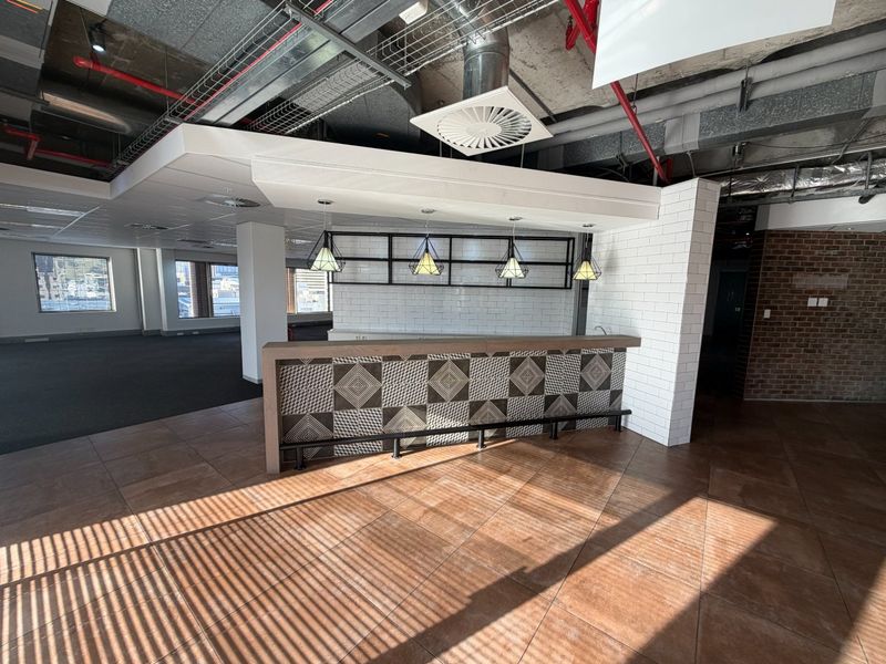 A modern commercial bar area featuring a decorative tiled counter, subway tile backsplash, and an industrial-style exposed ceiling with integrated lighting.