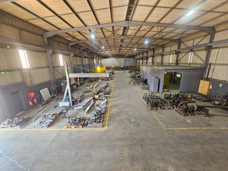 Spacious industrial warehouse featuring a steel portal frame structure, concrete flooring, and high-clearance ceilings, suitable for manufacturing or storage operations.