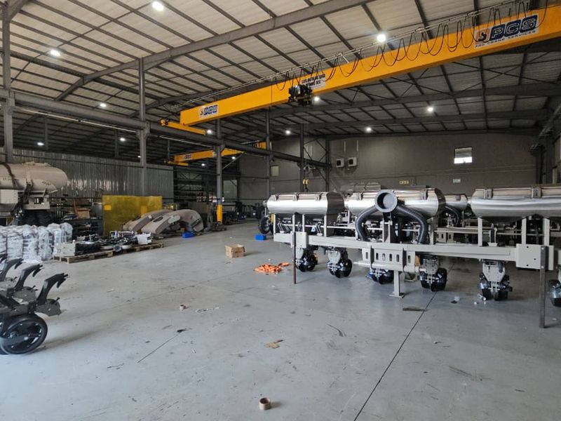 Spacious industrial warehouse facility featuring high ceilings, concrete flooring, and integrated overhead gantry cranes suitable for heavy manufacturing or storage operations.