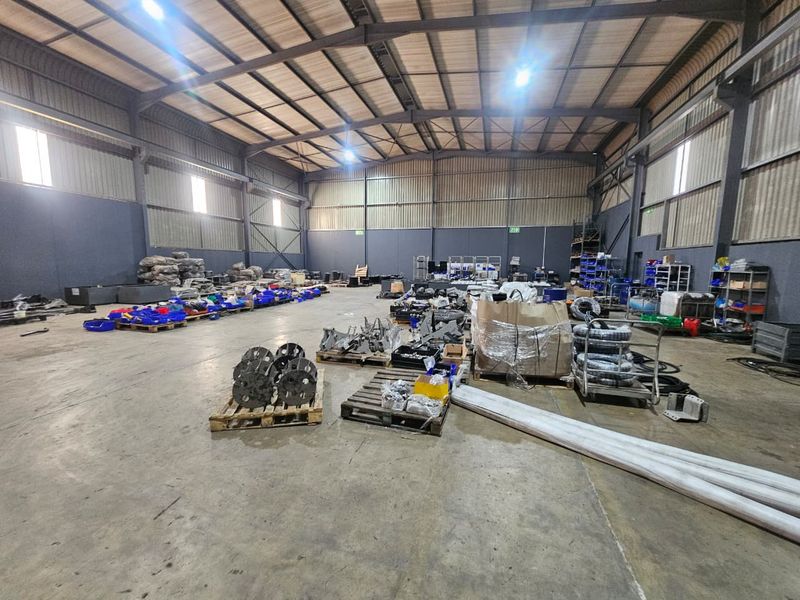 Spacious industrial warehouse featuring high-bay lighting, concrete flooring, and a robust steel portal frame structure suitable for storage or manufacturing operations.